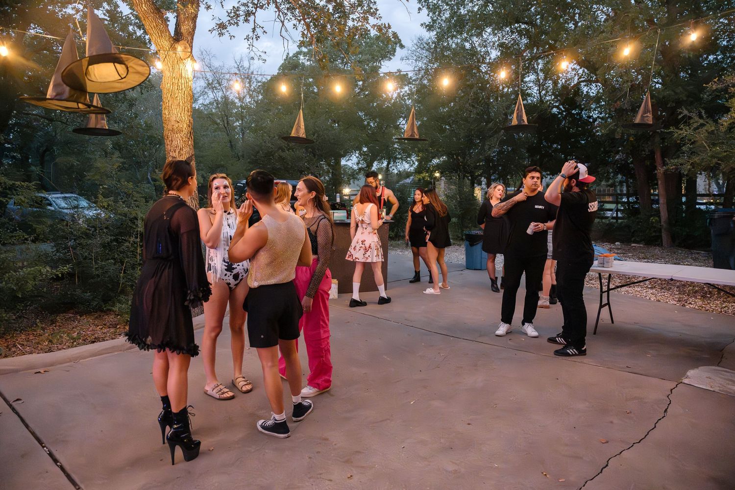 People dancing and socializing on a patio under string lights at dusk.