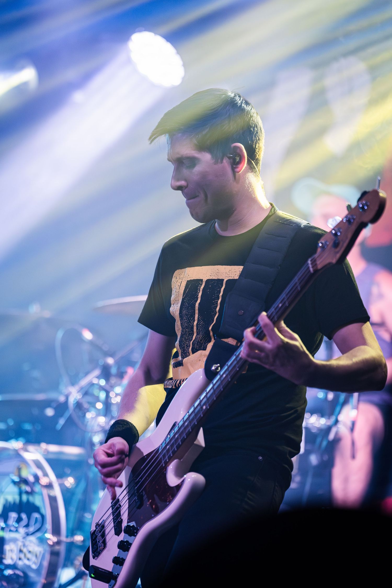 Bass guitarist performing on stage with dramatic lighting effects in the background.