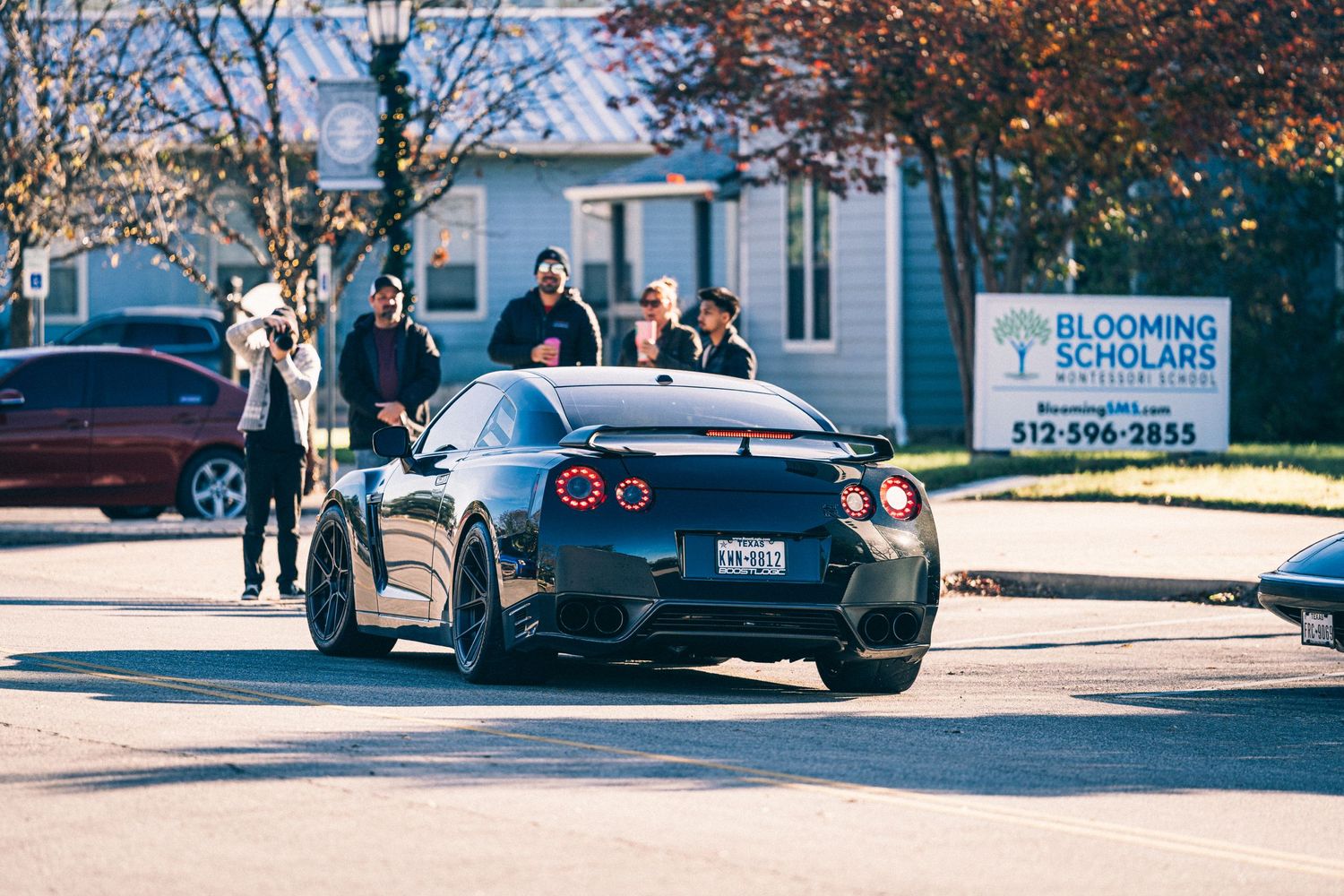 Black Nissan GT-R parked on a sunny street during a car meet.