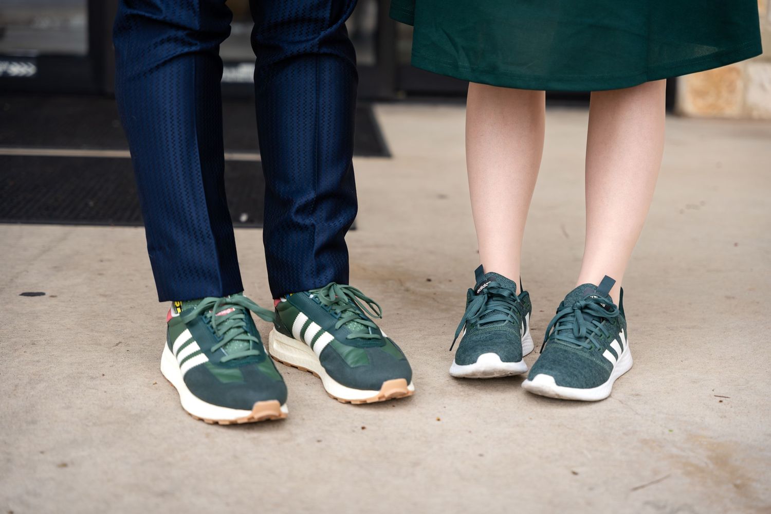 Two pairs of matching green sneakers shown side by side on concrete.