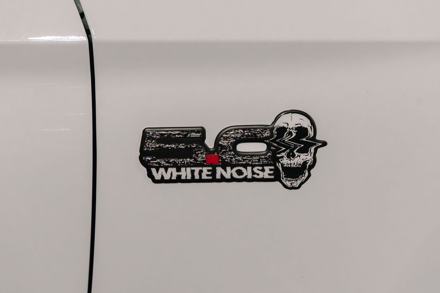 A close-up of a White Noise car emblem in black and white.