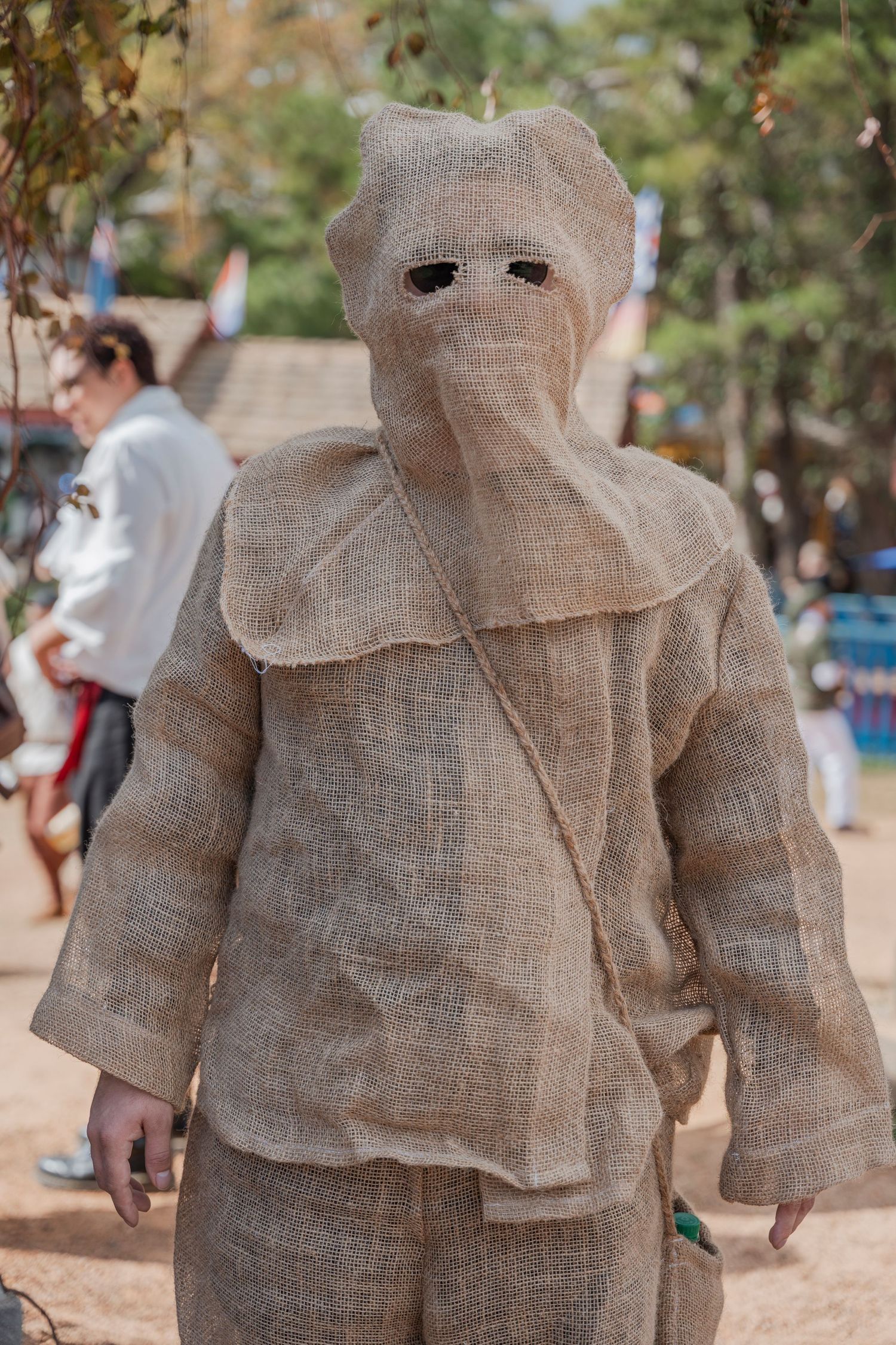 Performer dressed as mummy character in wrapped beige fabric costume at Renaissance fair.