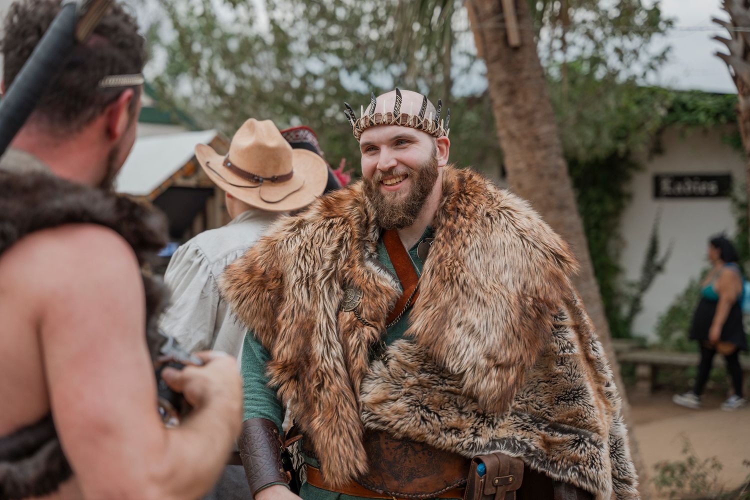 Festival participant wearing fur cloak and crown at renaissance faire.