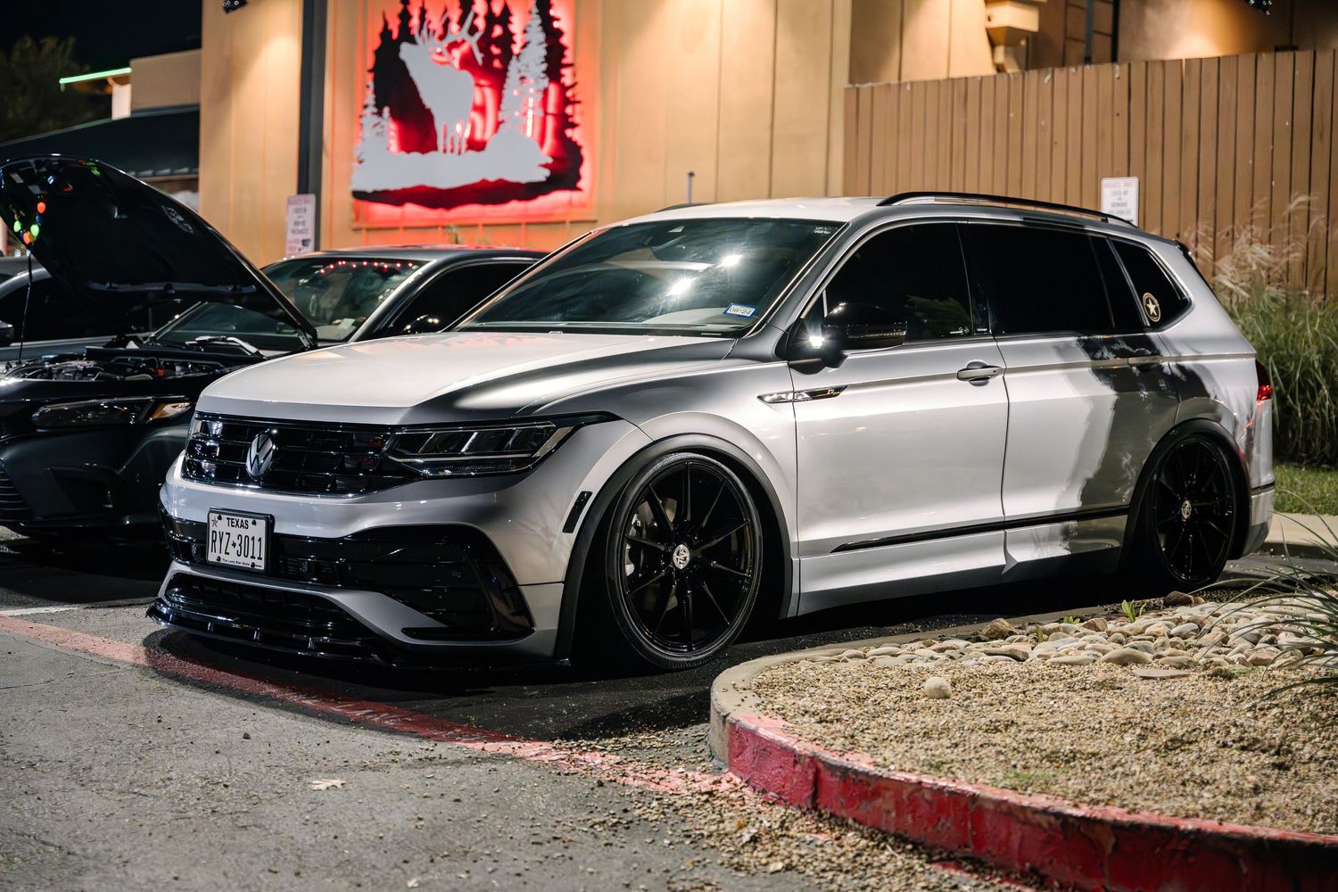 Lowered Volkswagen Tiguan R in silver with custom wheels parked at night.