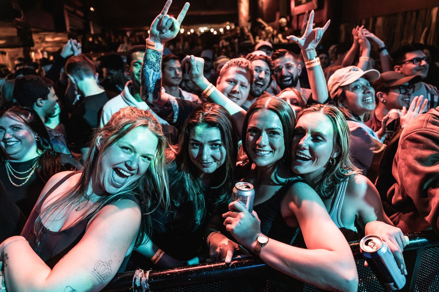 Concert crowd enjoying show at barrier with blue lighting effects.