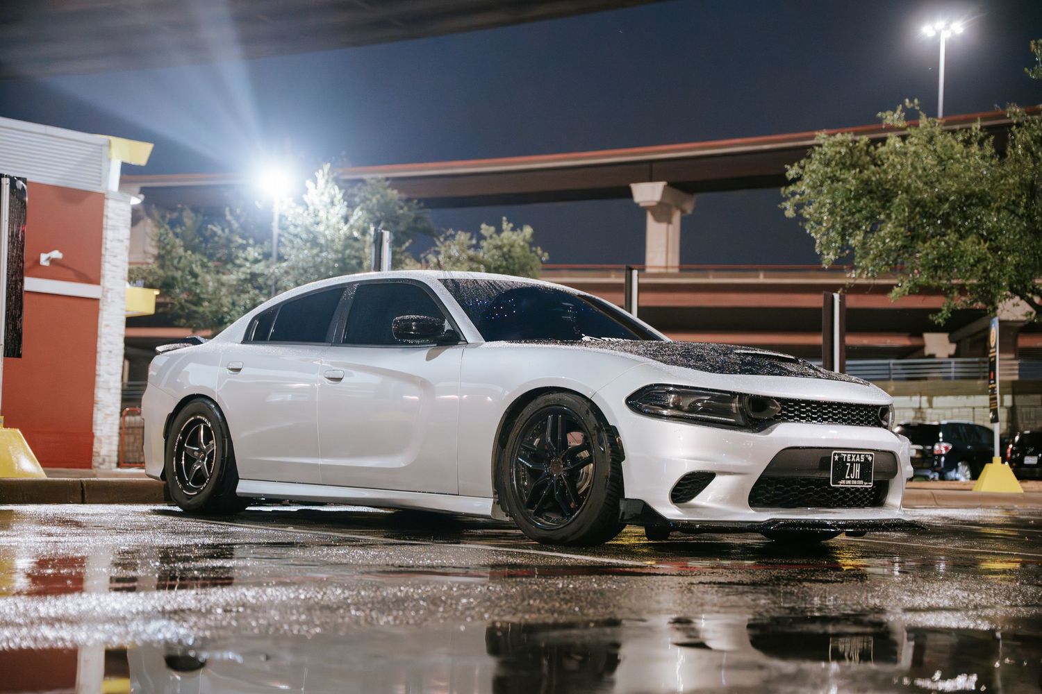 White Dodge Charger with custom wheels parked at a nighttime car meet.