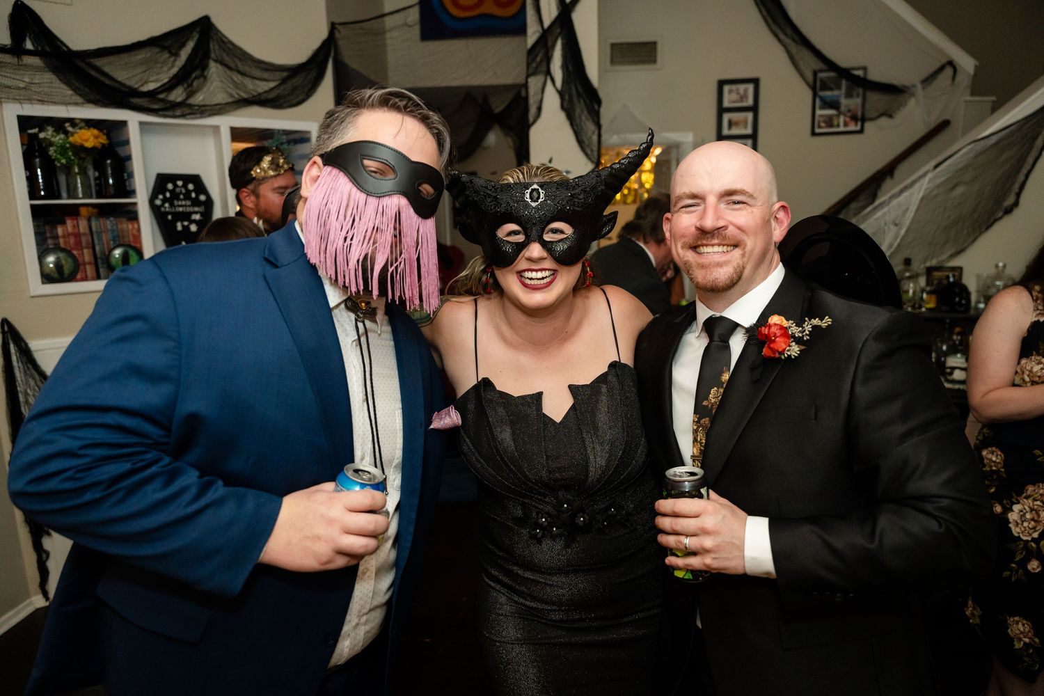 Wedding guests in masks and costumes pose together at a Halloween themed reception.