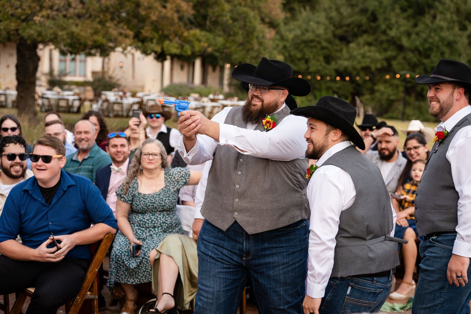 Wedding party members in western attire perform for guests during outdoor celebration.