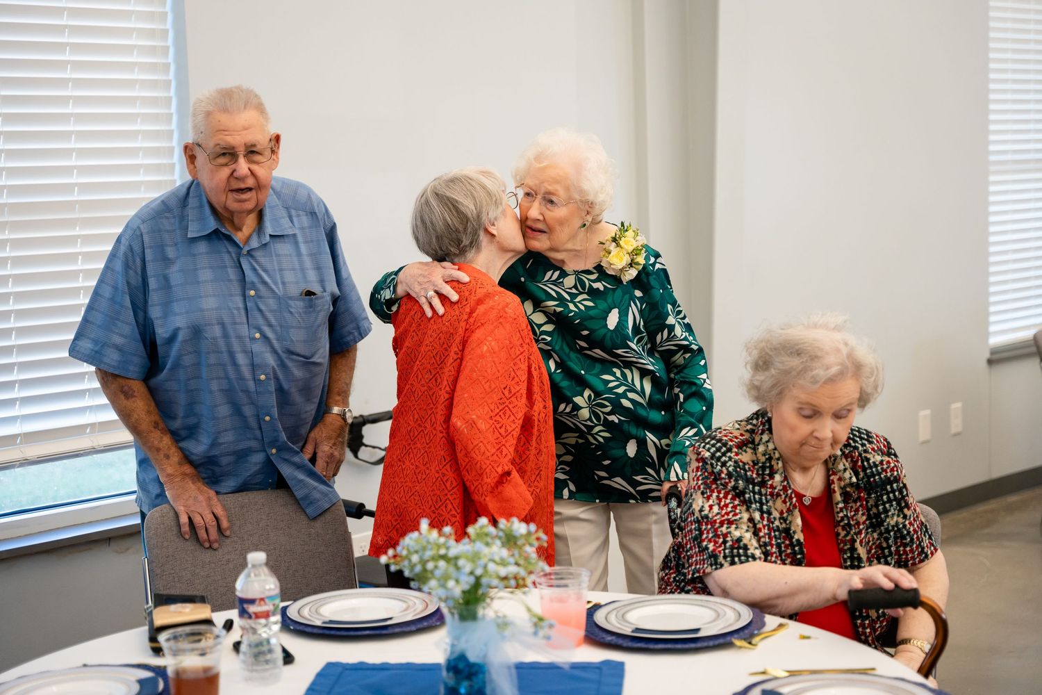 A casual gathering around a table with blue tablecloths and place settings.