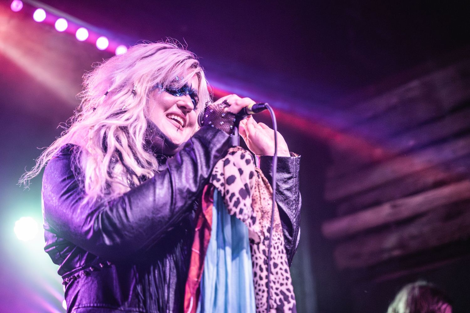 Dynamic stage performance with pink and purple lighting effects.