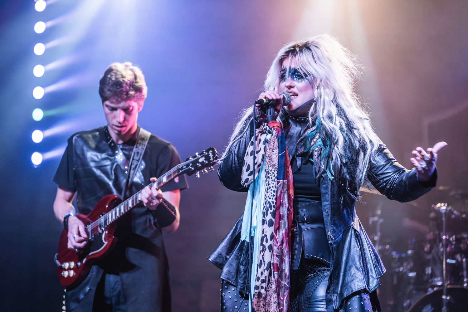 Band performs on stage with dramatic lighting effects and theatrical atmosphere during live concert.