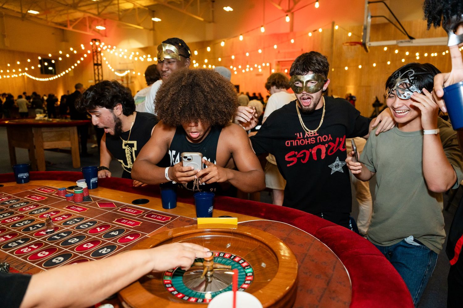Players gathered around a roulette table reacting to a game in progress.
