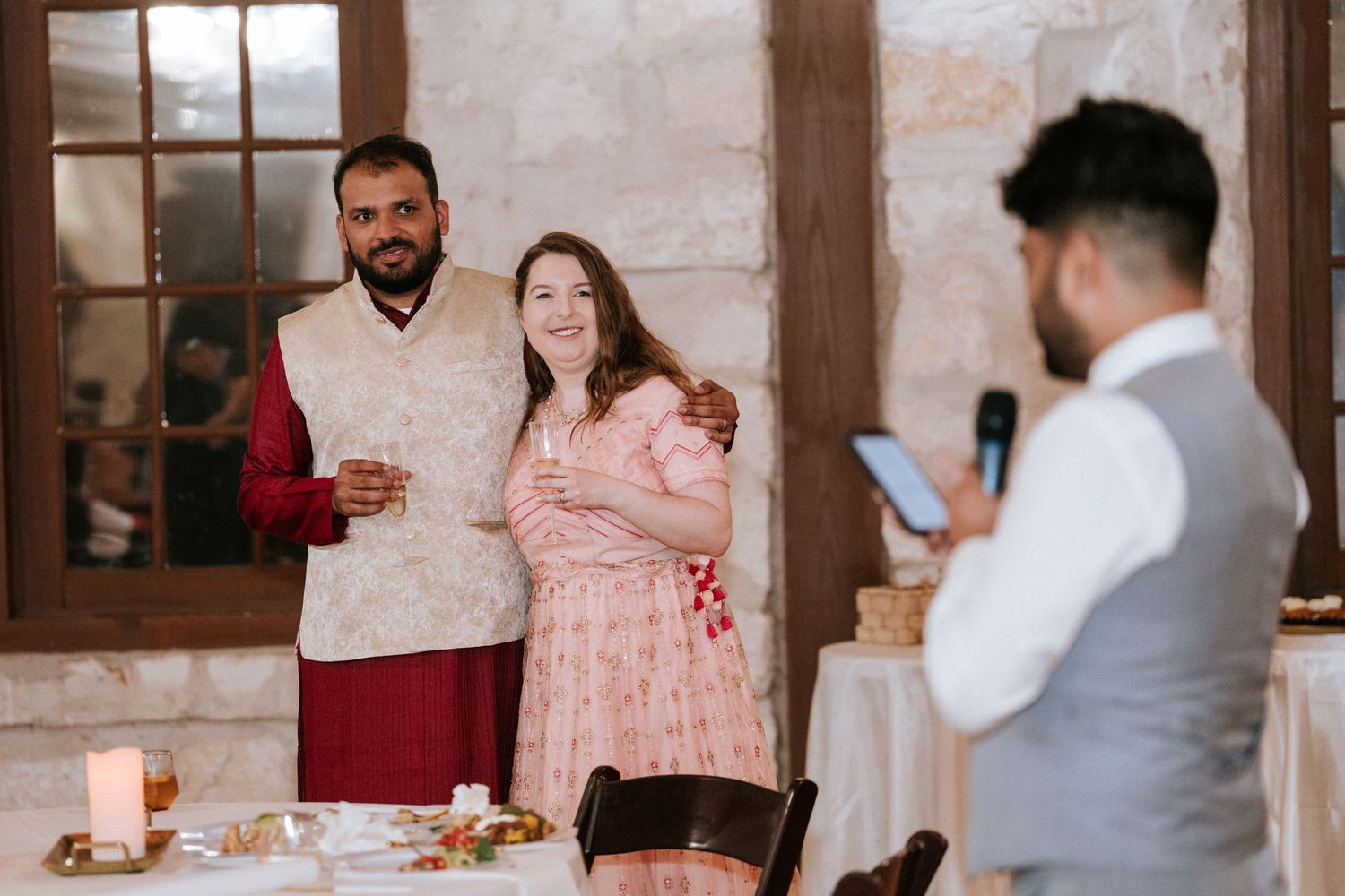 Wedding guests share toasts and laughter during an intimate indoor celebration.