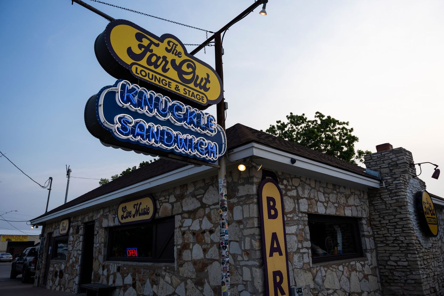 A vintage neon sign for Jerry's Frozen Custard glows against a dusk sky above a stone-faced restaurant building.