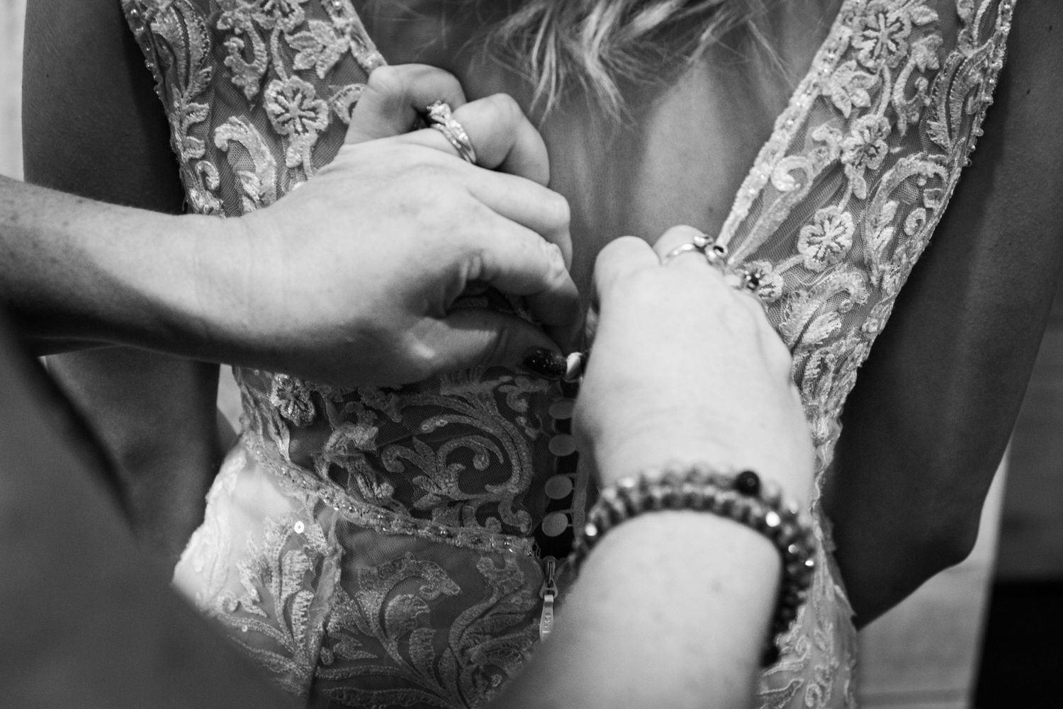 Black and white detail shot of hands fastening dress buttons.