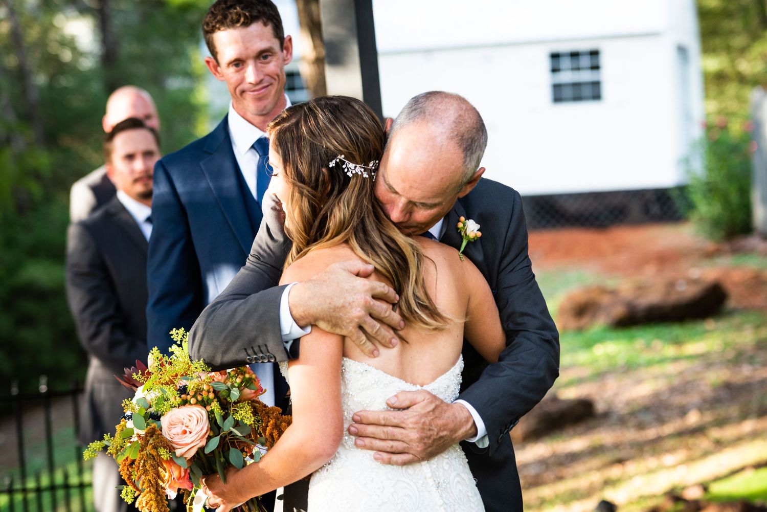 An intimate moment shared during an outdoor wedding ceremony with a fall bouquet of yellow flowers.