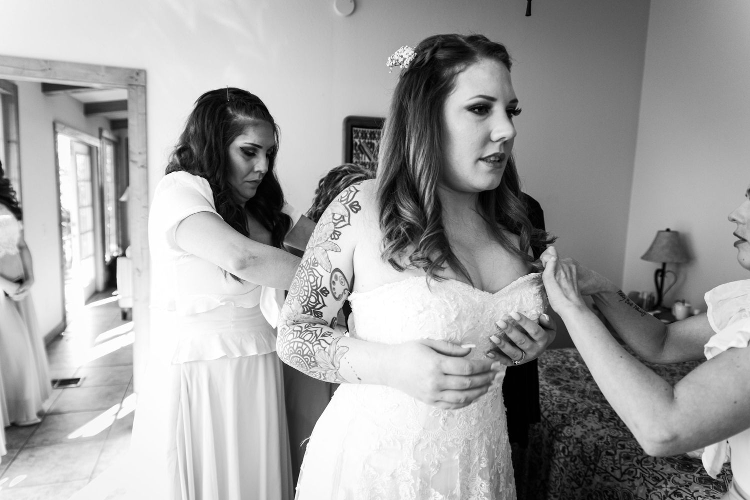 A moment of preparation in a bridal suite with white lace dresses.