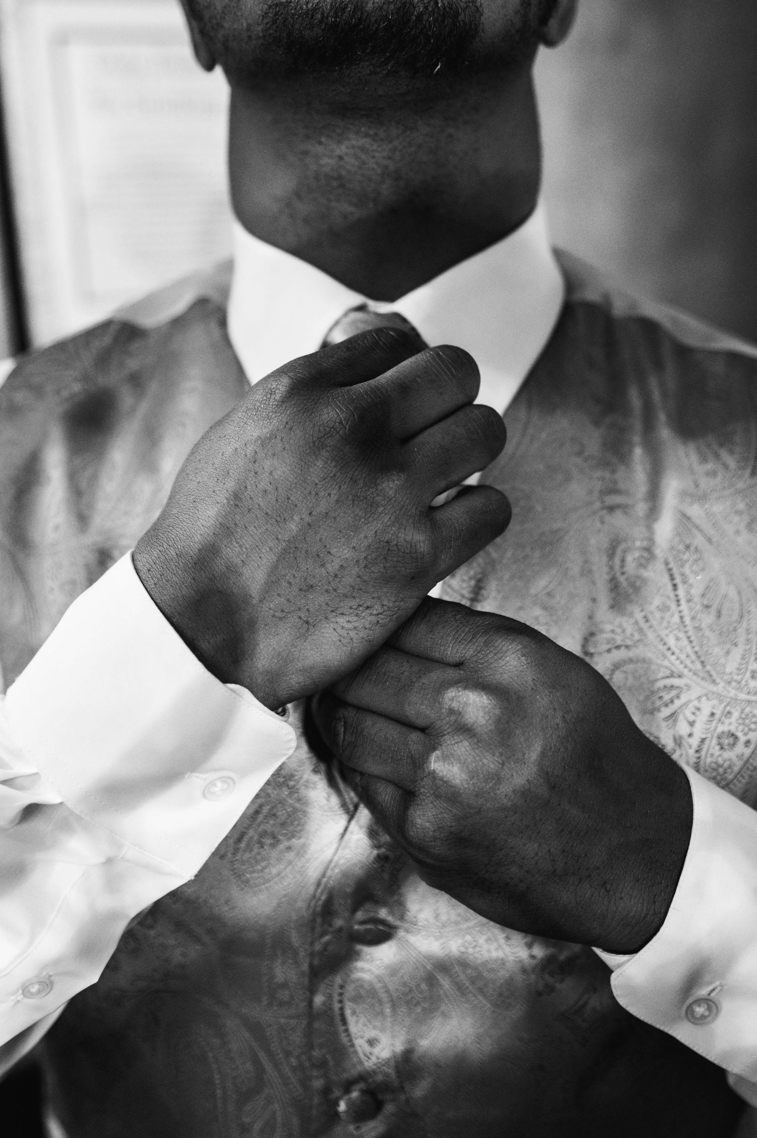Black and white close-up of hands adjusting formal attire.