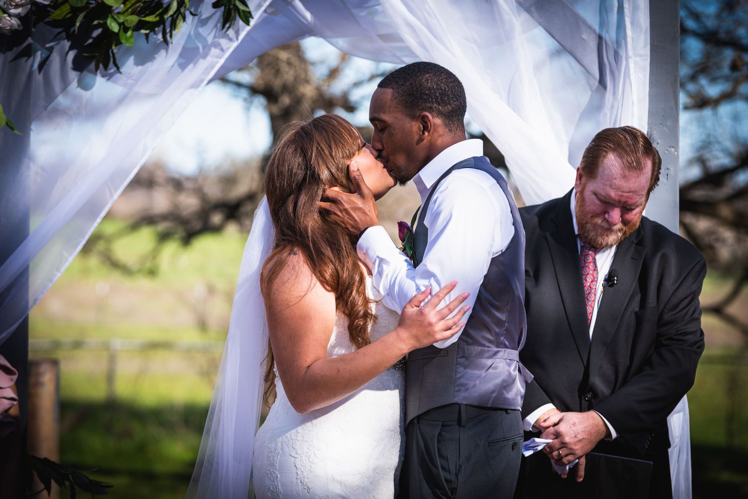 The couple shares their first kiss during the outdoor wedding ceremony.