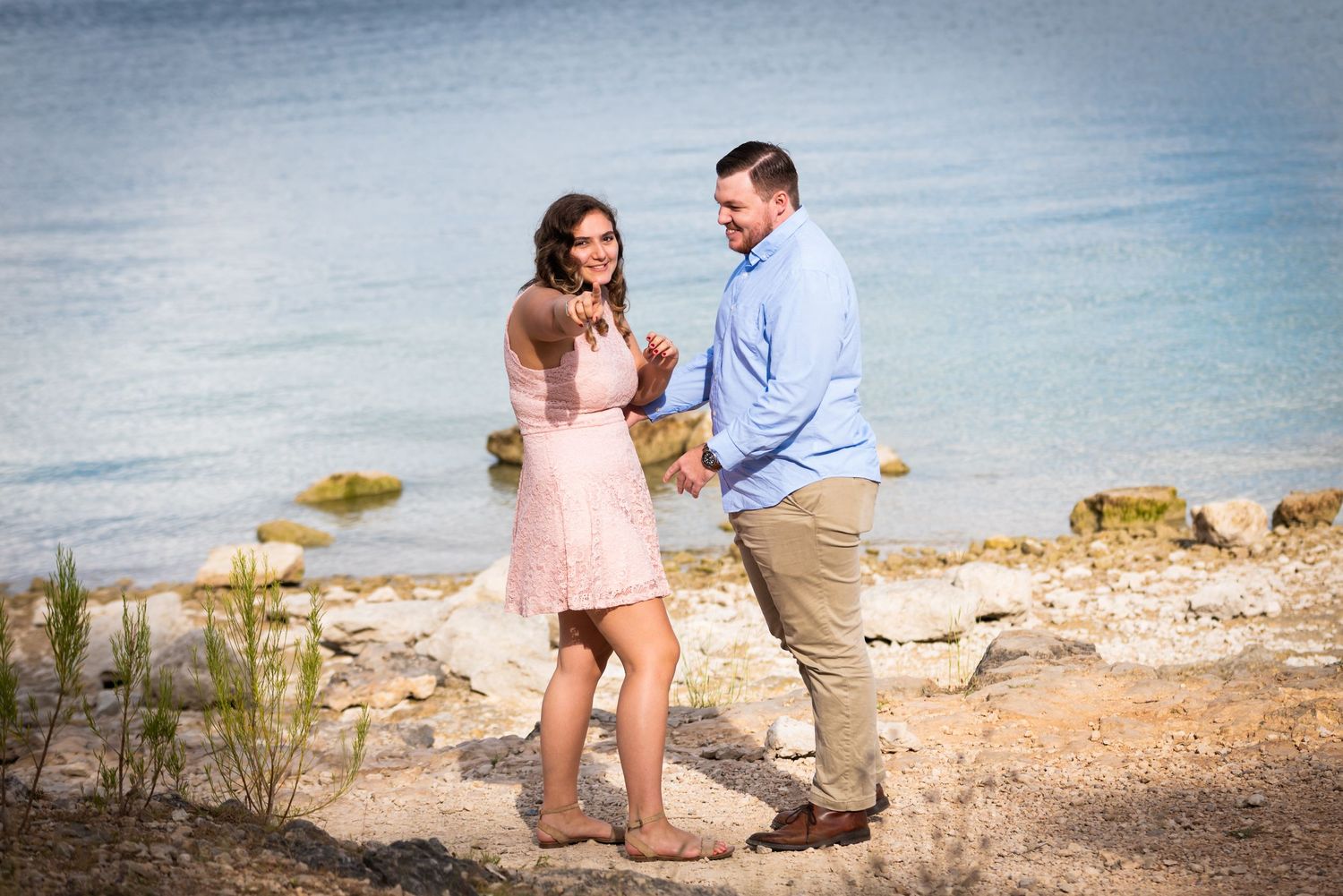A joyful moment shared between two people on a rocky coastal overlook.
