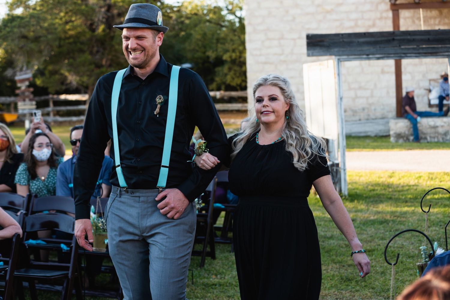 A couple walks arm in arm during an outdoor wedding ceremony with turquoise accents.