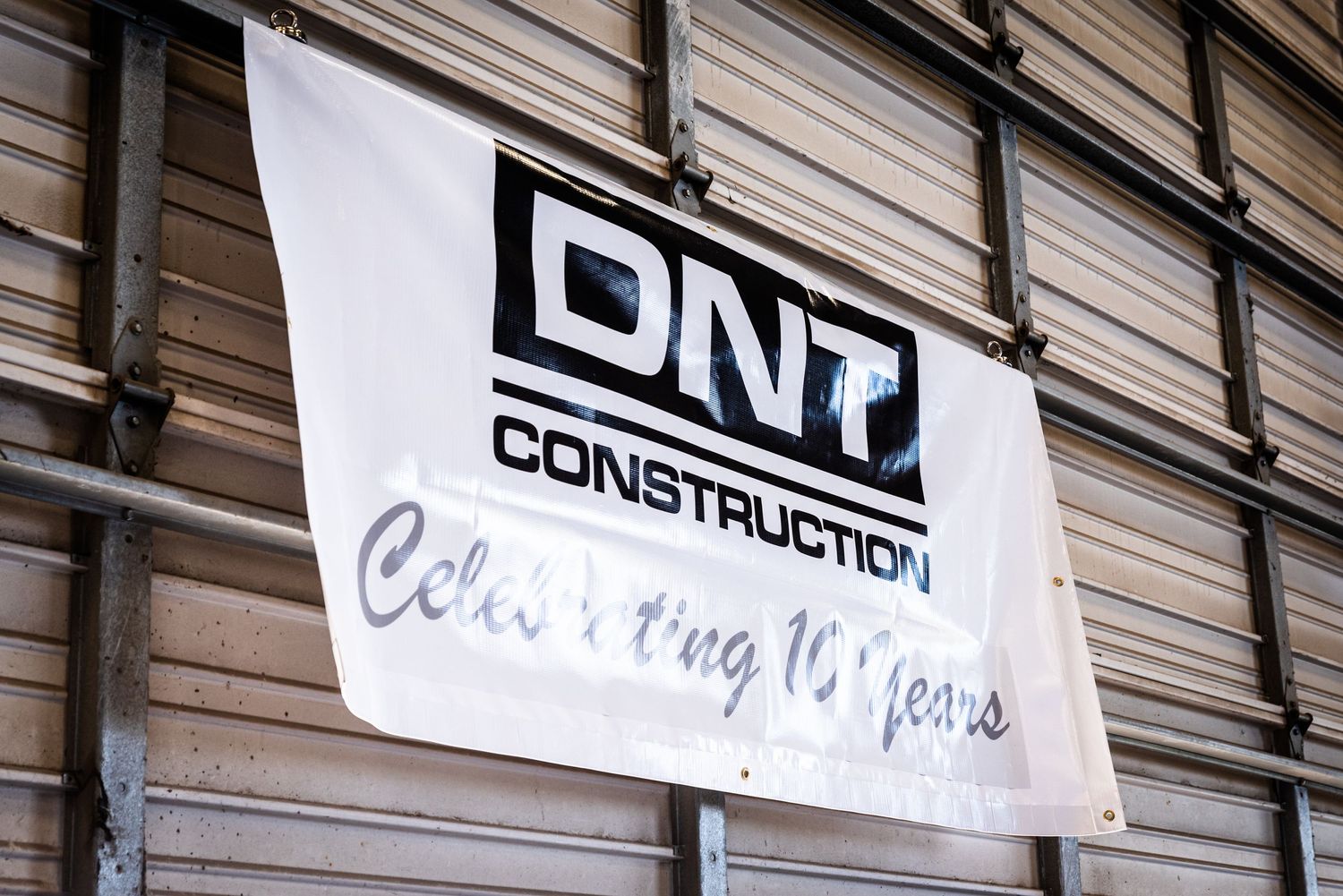 A white banner displaying 'DNt Construction' text mounted on a wooden wall surface.