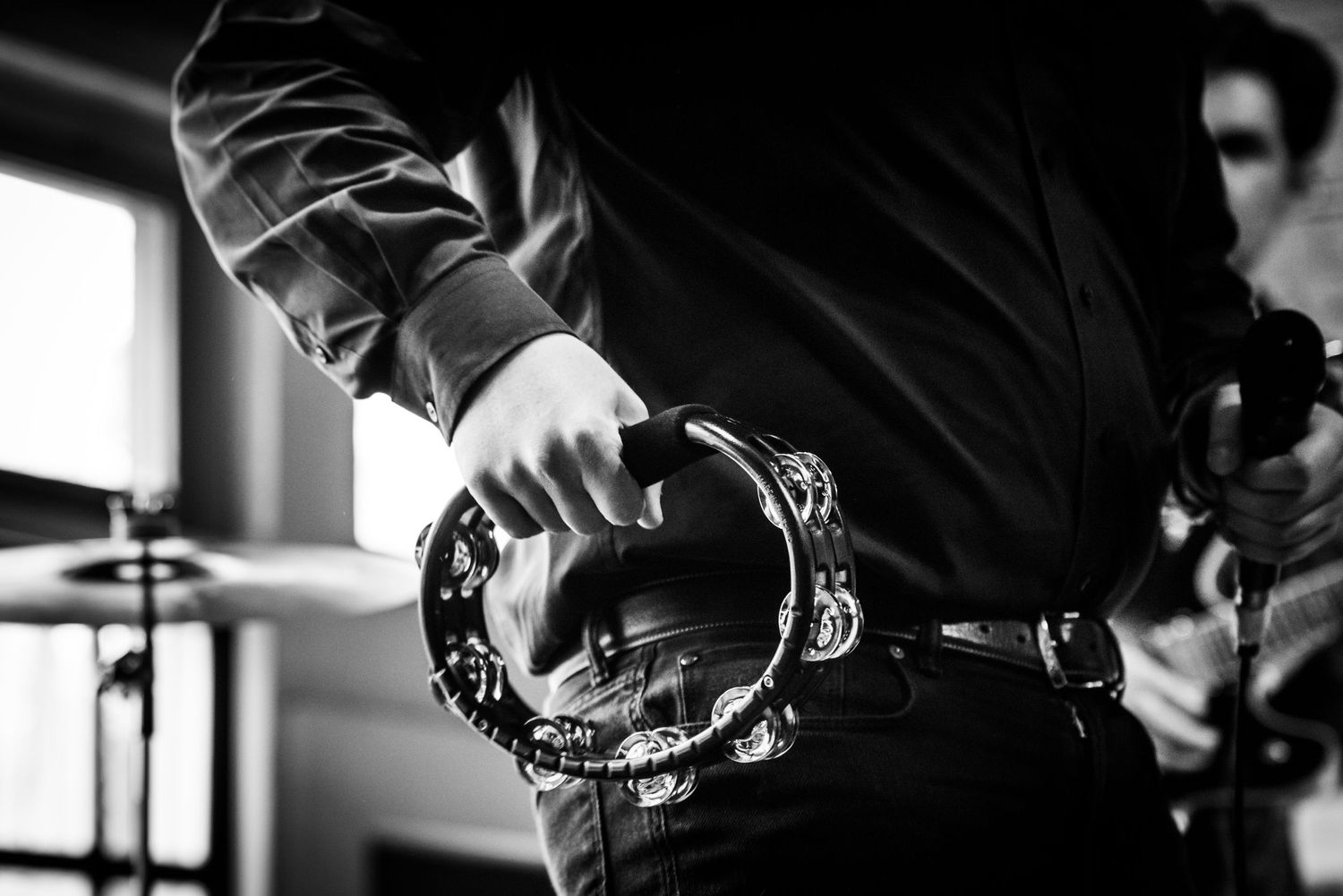Black and white close-up of hands holding tambourine during musical performance.