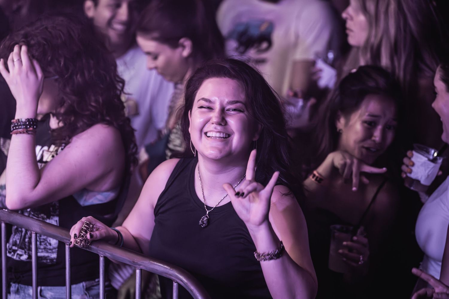 Concert attendees smile and dance while enjoying live music performance.