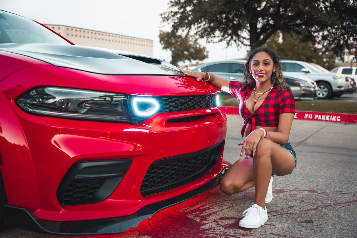 Bright red Dodge Charger with glowing blue badge displayed at car show.