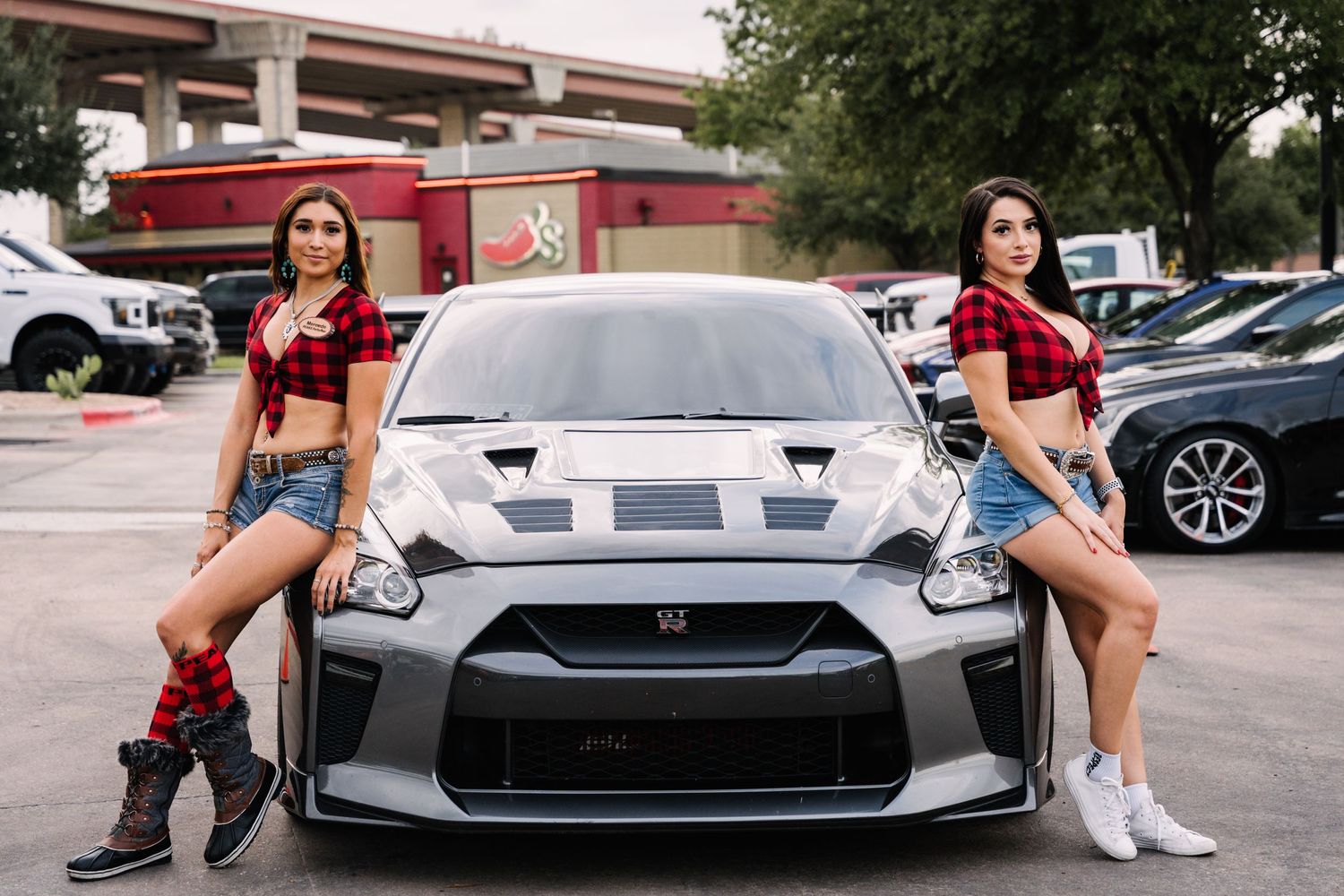Gray Nissan GT-R displayed at car show with matching red and denim outfits.