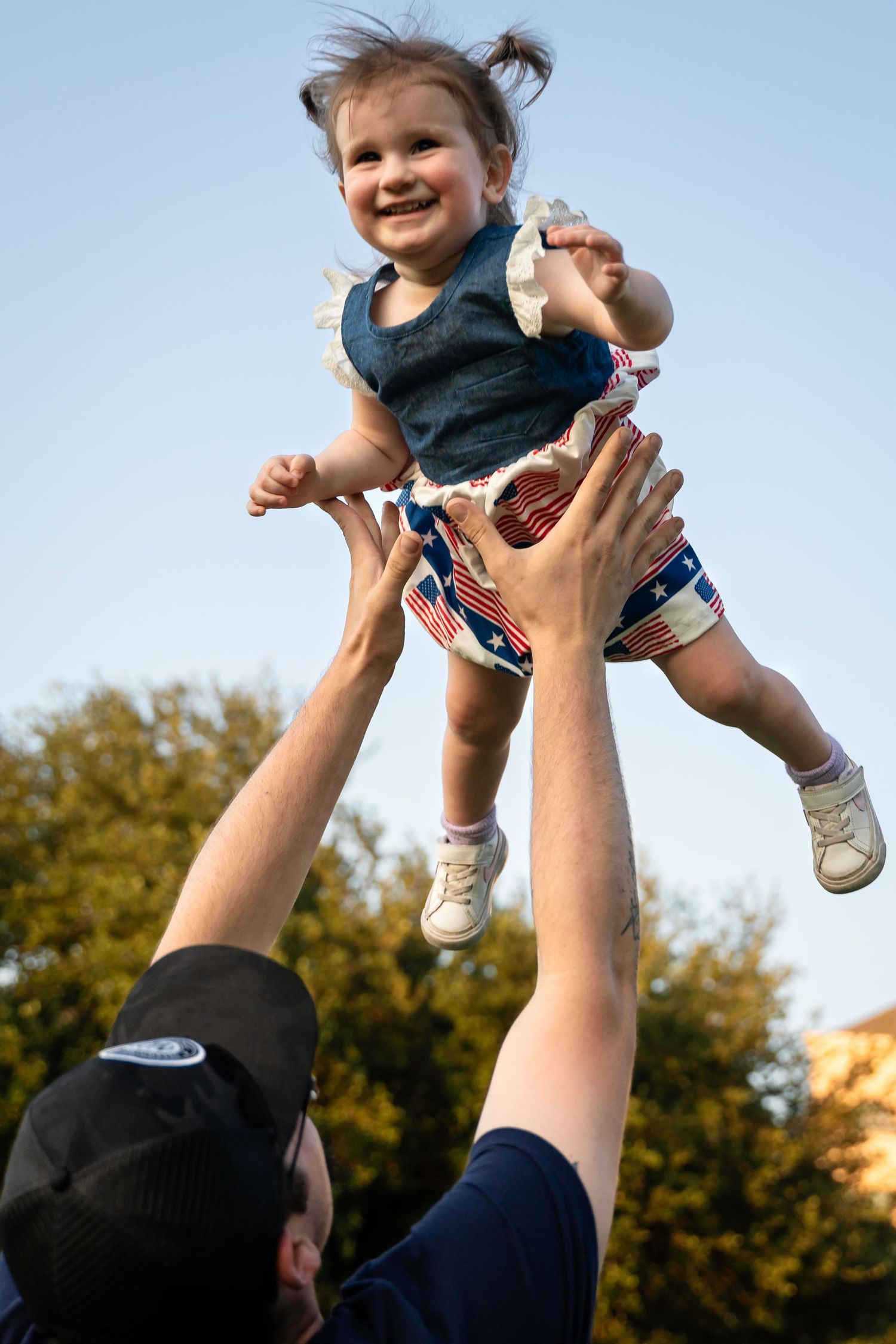 A joyful moment captured against blue sky as someone is lifted high into the air.