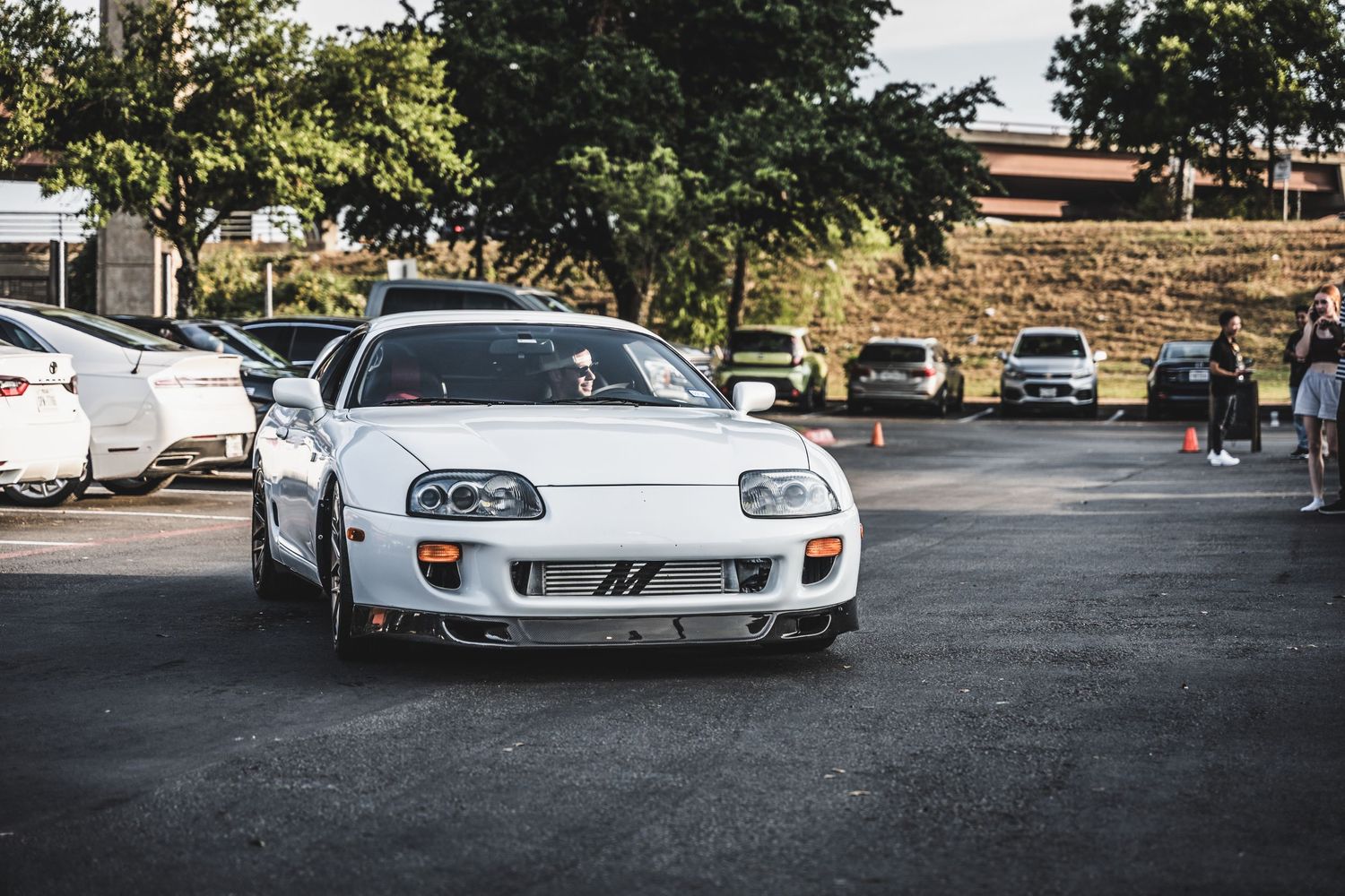White Toyota Supra MK4 parked in a lot during a car meet.
