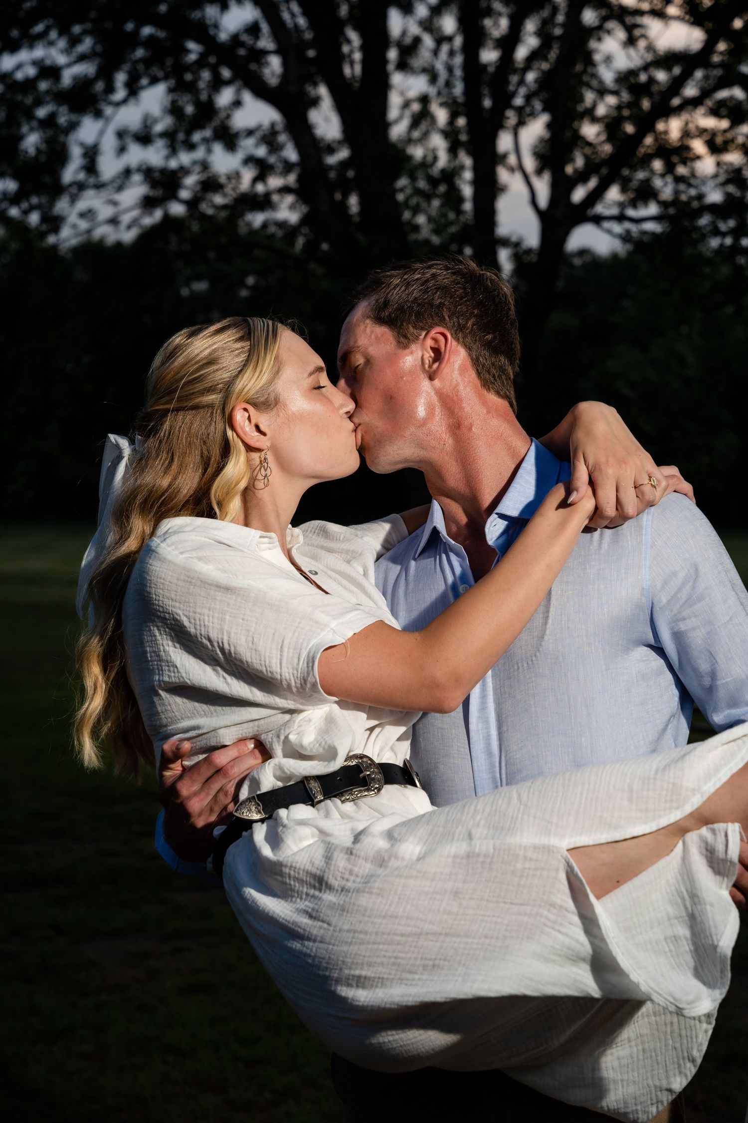 Intimate sunset portrait of a couple sharing a romantic dip pose in a park setting.
