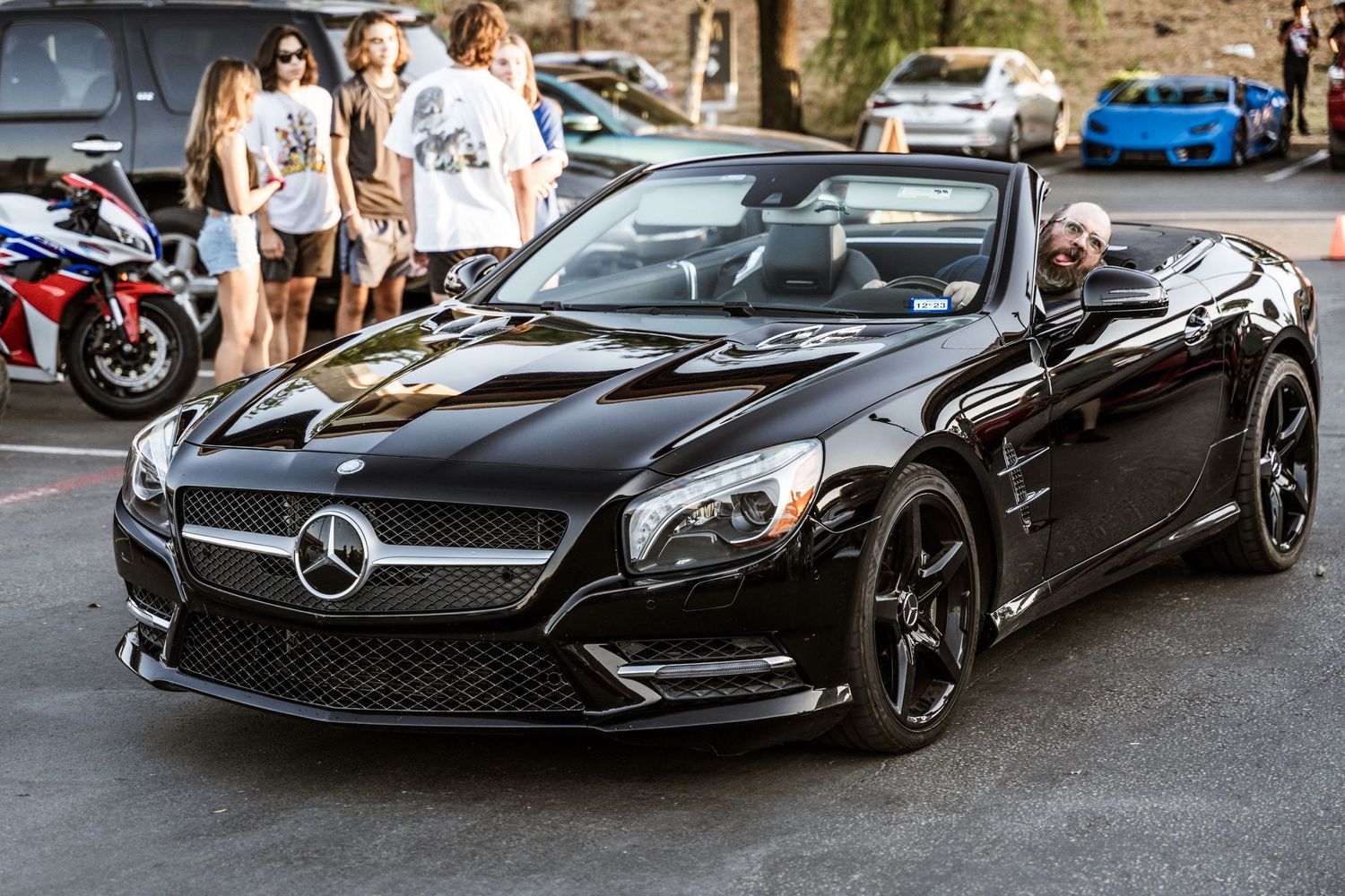 A sleek black Mercedes-Benz SL convertible parked at a car meet.