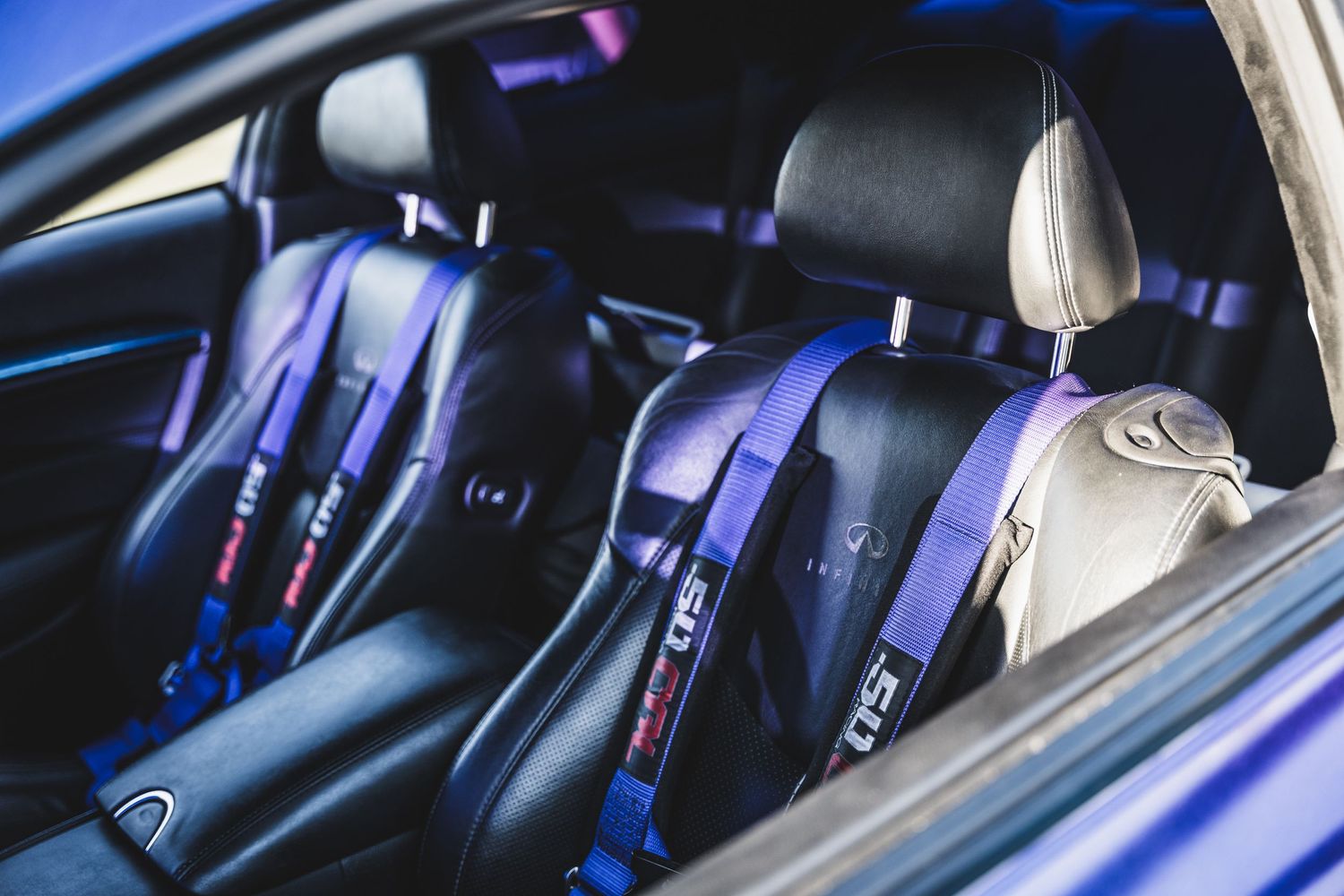 Custom interior featuring purple racing harnesses and black leather seats.