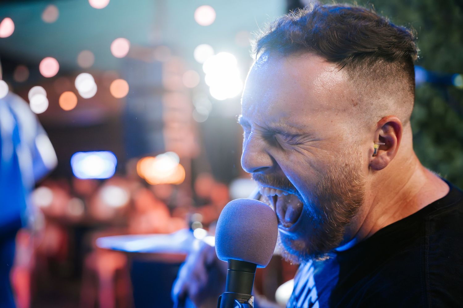 Performer sings passionately into microphone during nighttime concert.
