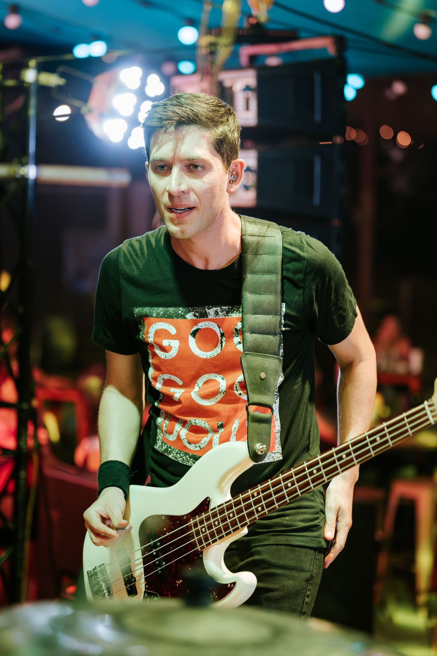 Bass guitarist performing on stage with focused expression under stage lights.