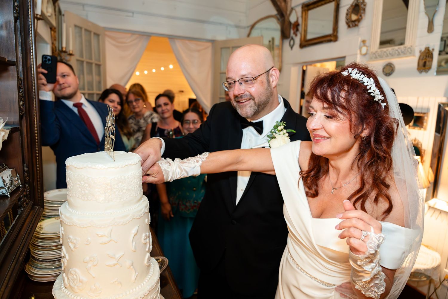 A couple cutting their white wedding cake together during their reception celebration.