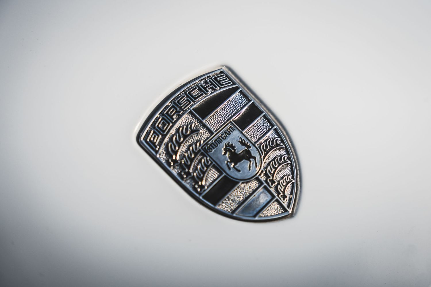 Close-up detail of metallic Porsche crest badge emblem.