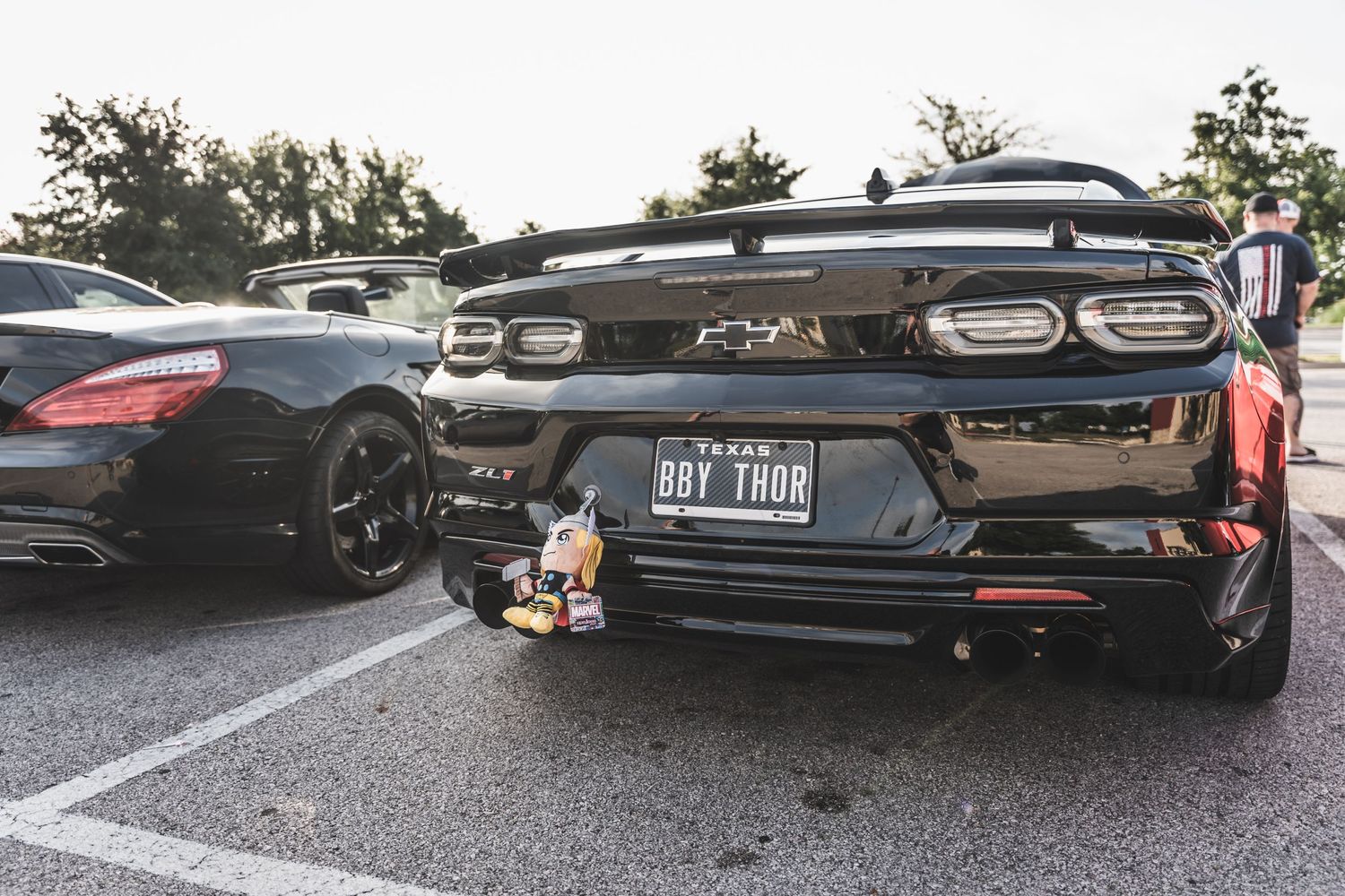 Rear view of modern performance cars parked with decorative toys on bumpers.