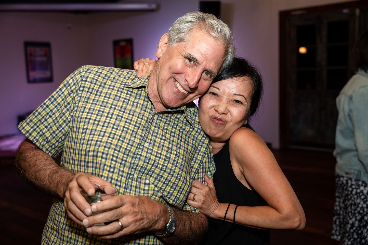 A couple shares a warm embrace during an evening social gathering.