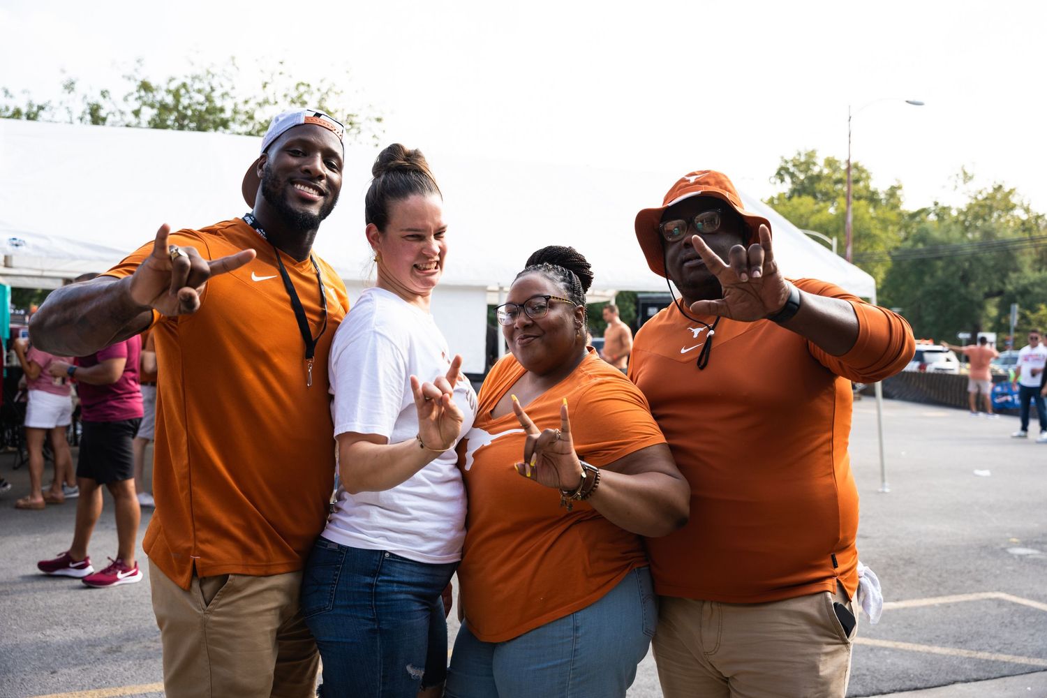 A group wearing orange and white team colors celebrates together at a tailgate party.