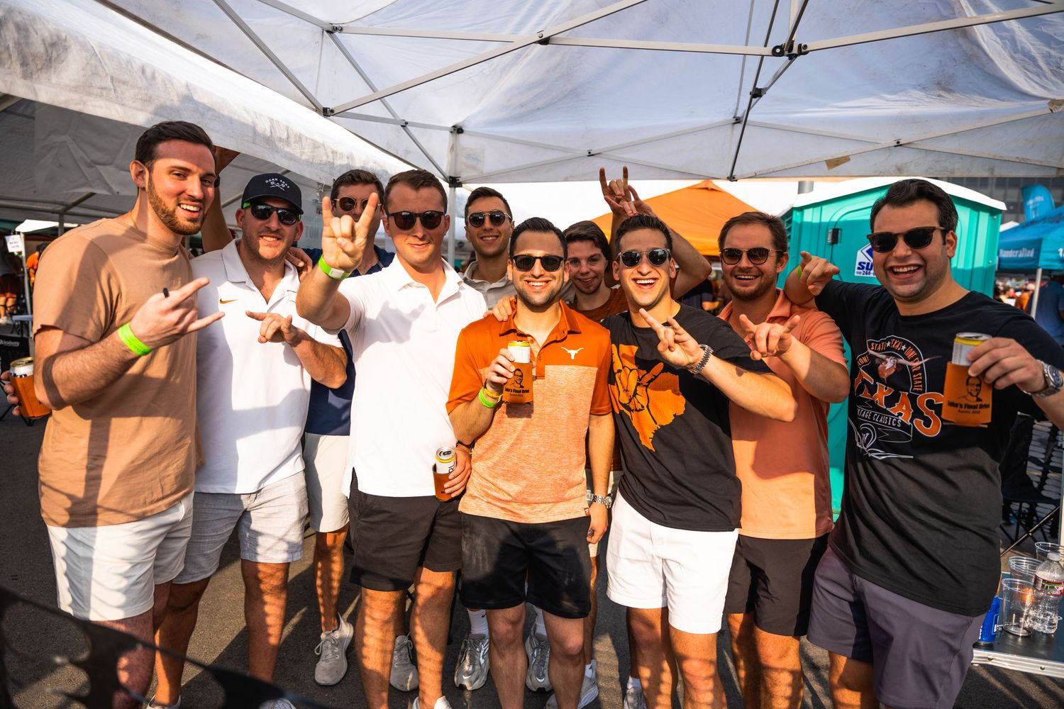 Friends making hand gestures while posing together at outdoor gathering.