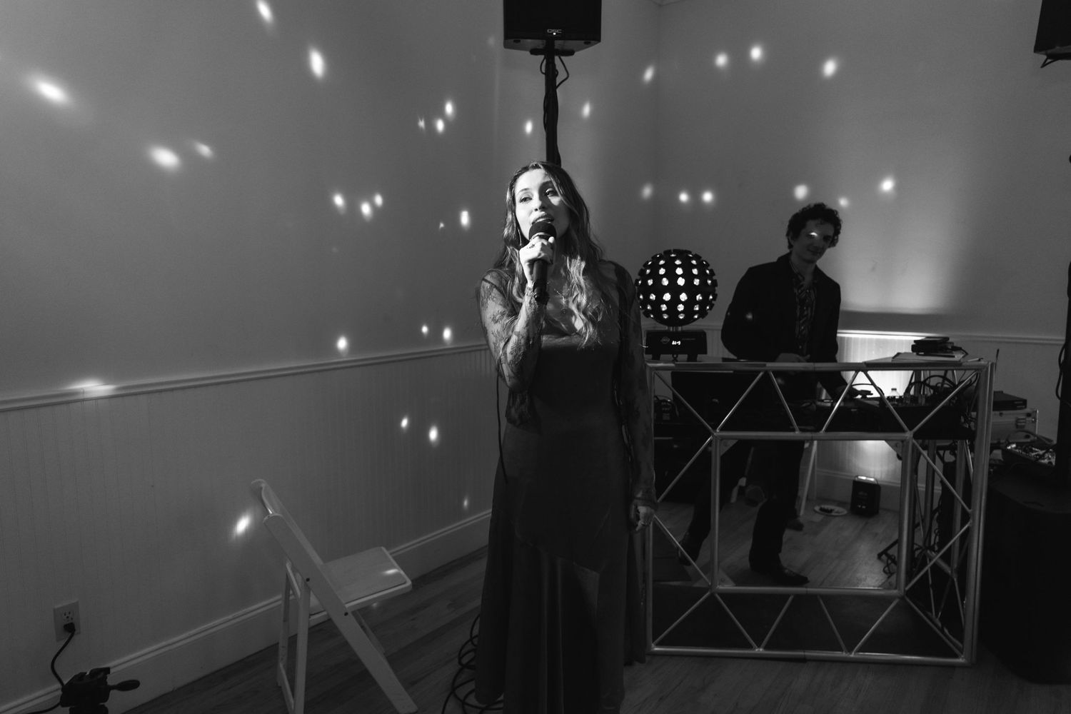 A performer in a dark dress sings on stage with sparkling lights creating a dreamy atmosphere.