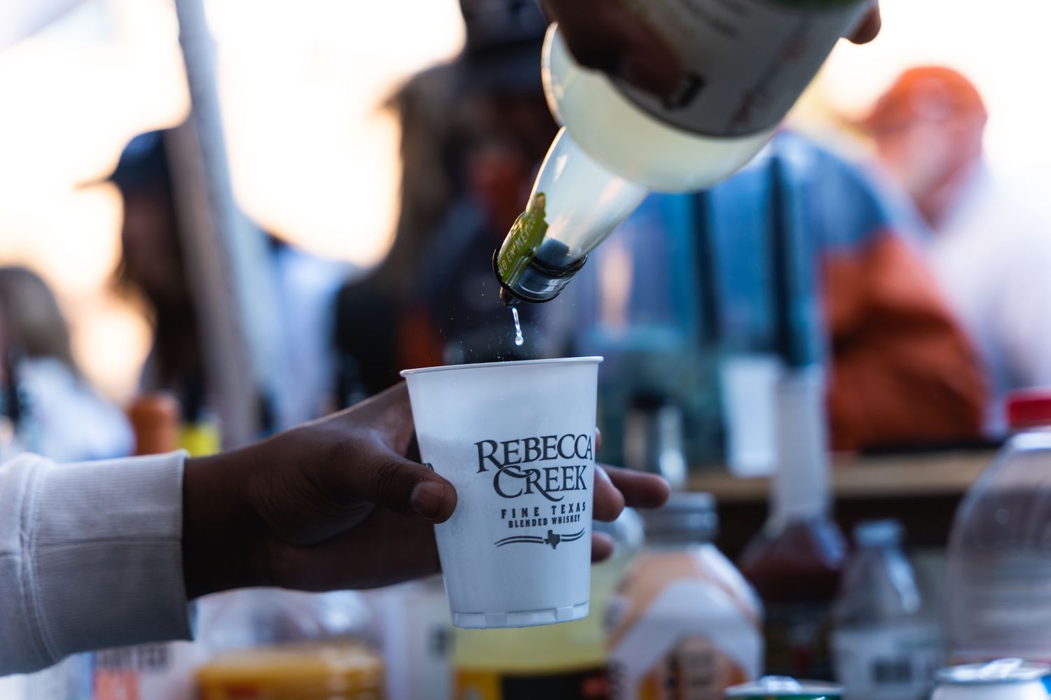 Liquid being poured into a disposable cup at an outdoor beverage station.