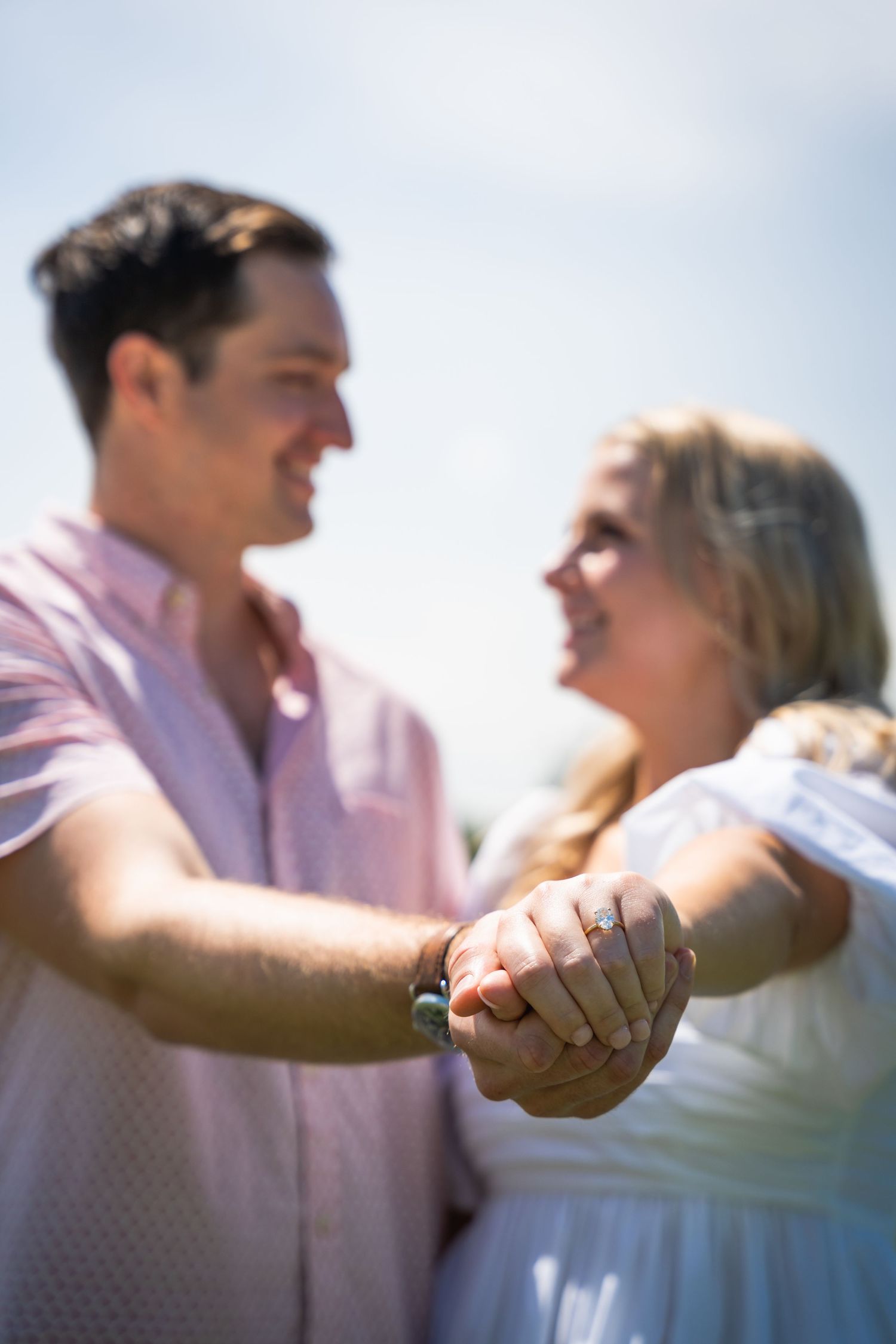A soft-focus romantic moment showing clasped hands of a couple in sunlight.