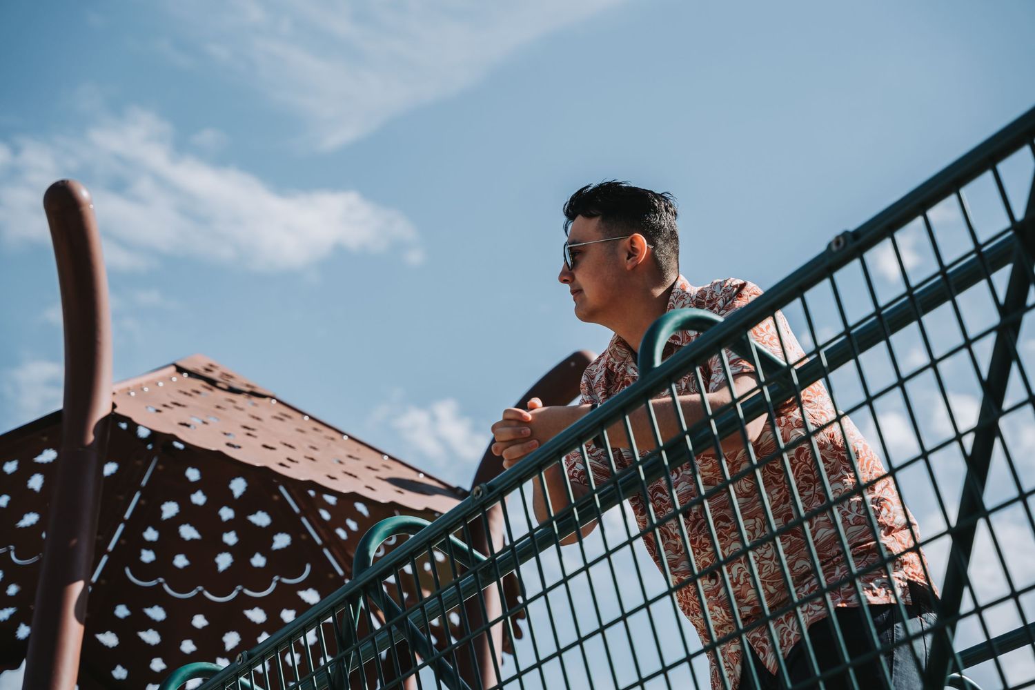 Side view of someone looking over playground equipment against blue sky.