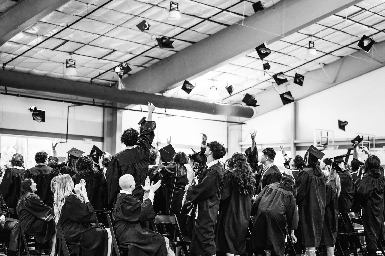 Graduation ceremony captured in black and white as students throw caps in celebration.
