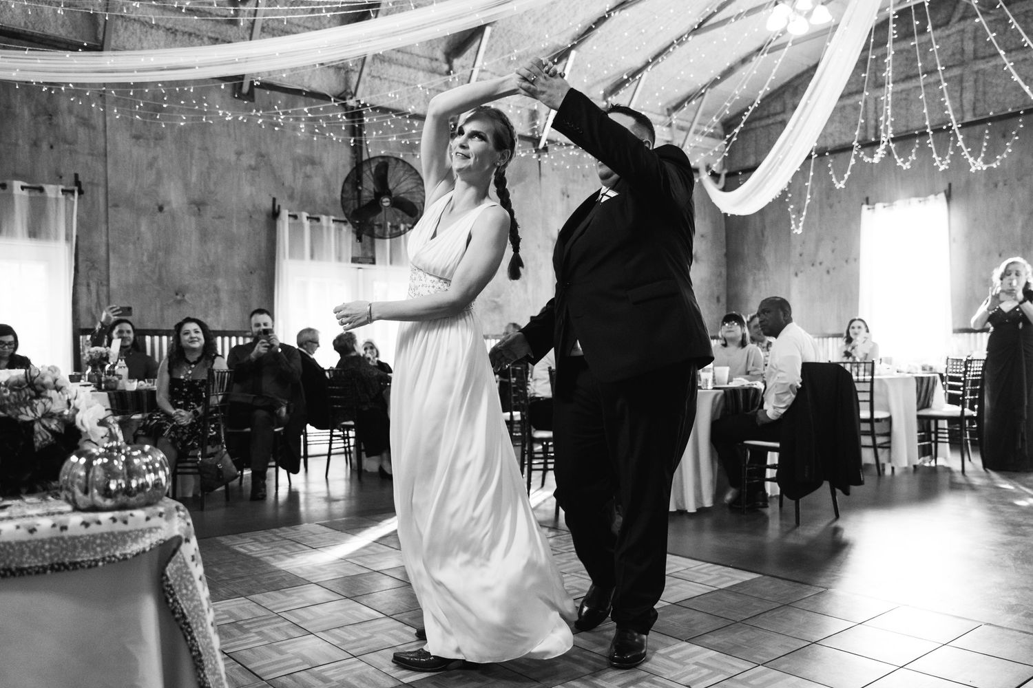 A joyful black and white photo of a couple dancing at their wedding reception.