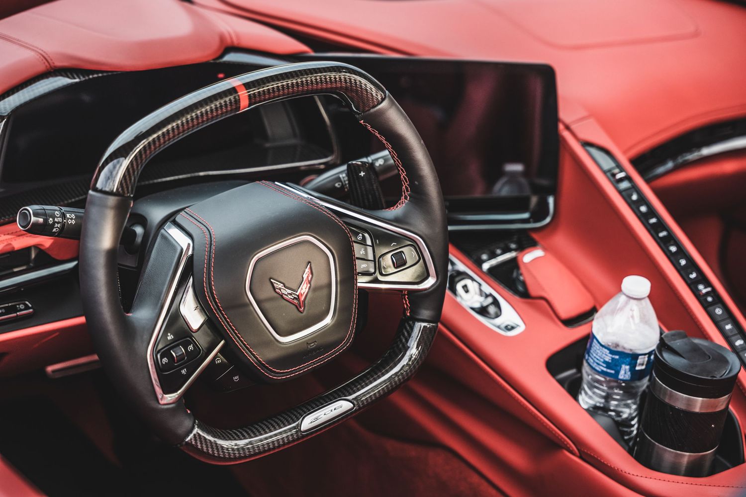 Interior view of a Corvette steering wheel and dashboard with red leather upholstery.